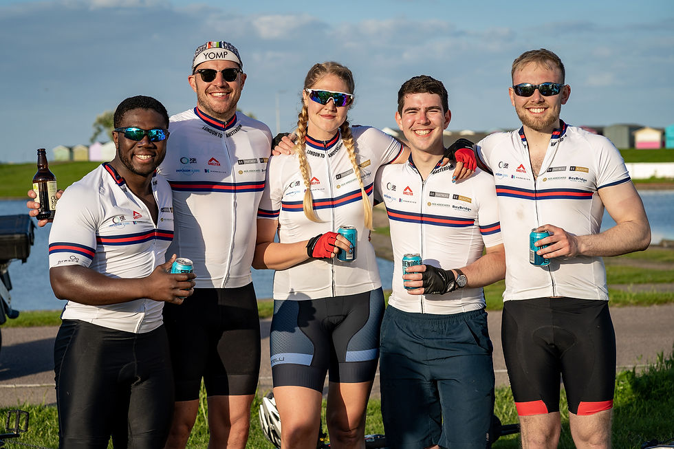 Five cyclists standing together, holding cans and smiling to camera