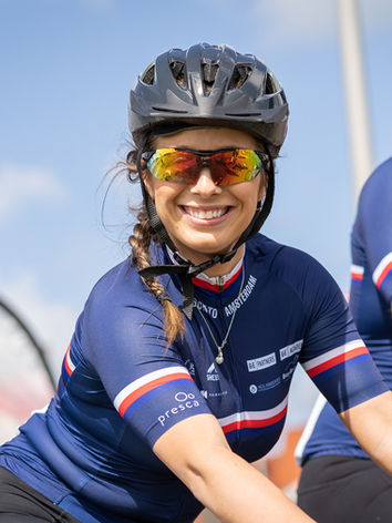Female cyclist smiling to camera in a blue cycling jersey