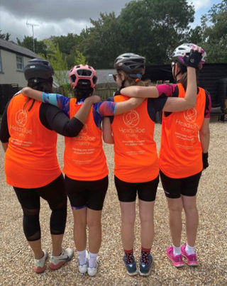 4 Cyclists in orange vests and helmets with back to camera