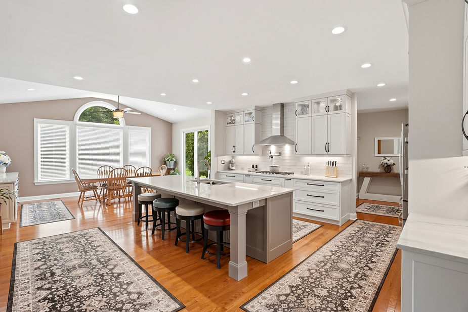 Elegant open-concept kitchen remodel with gray island cabinetry, white perimeter cabinets, quartz countertops, hardwood flooring, and a connected dining space.