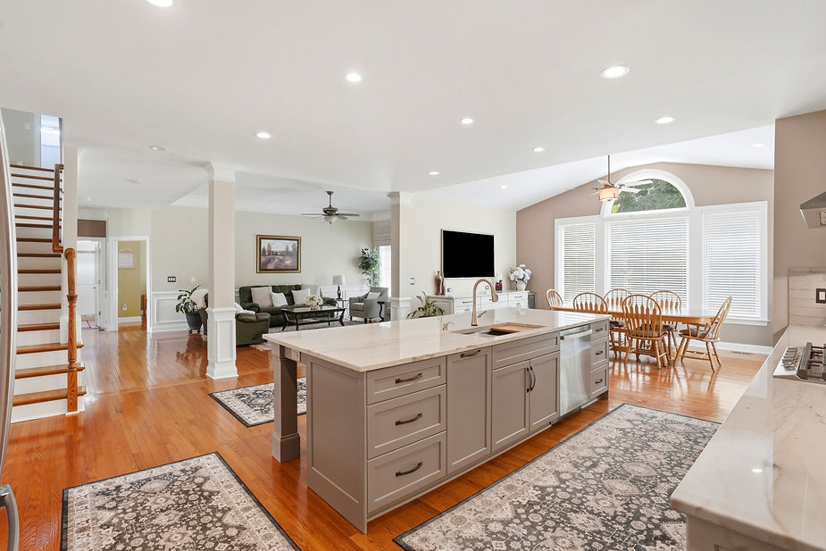 Bright open-concept kitchen remodel with a large gray island, white shaker cabinets, quartz countertops, stainless steel appliances, and seamless flow into the dining and living areas.