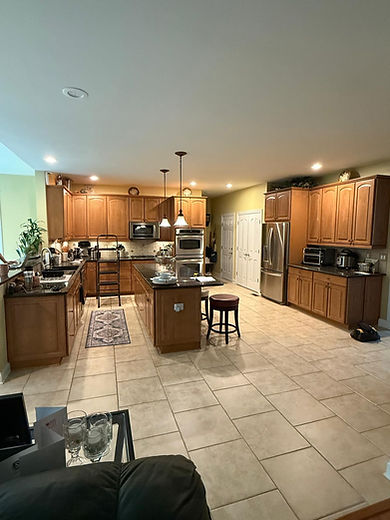 Wide view of the original kitchen before remodeling with oak cabinetry, center island, peninsula, stainless steel appliances, granite countertops, and an enclosed layout.