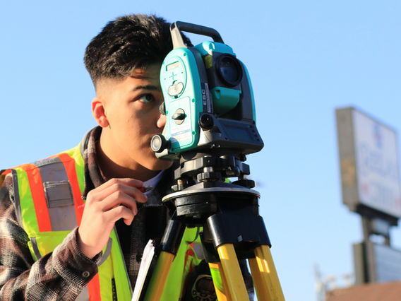 A young person in high vis looks into engineering equipment