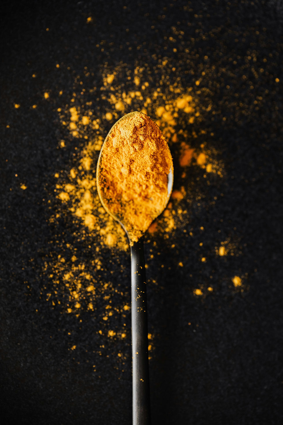 Fresh, vibrant homegrown ground turmeric powder on a wooden spoon, showcasing its natural teeth-whitening properties.