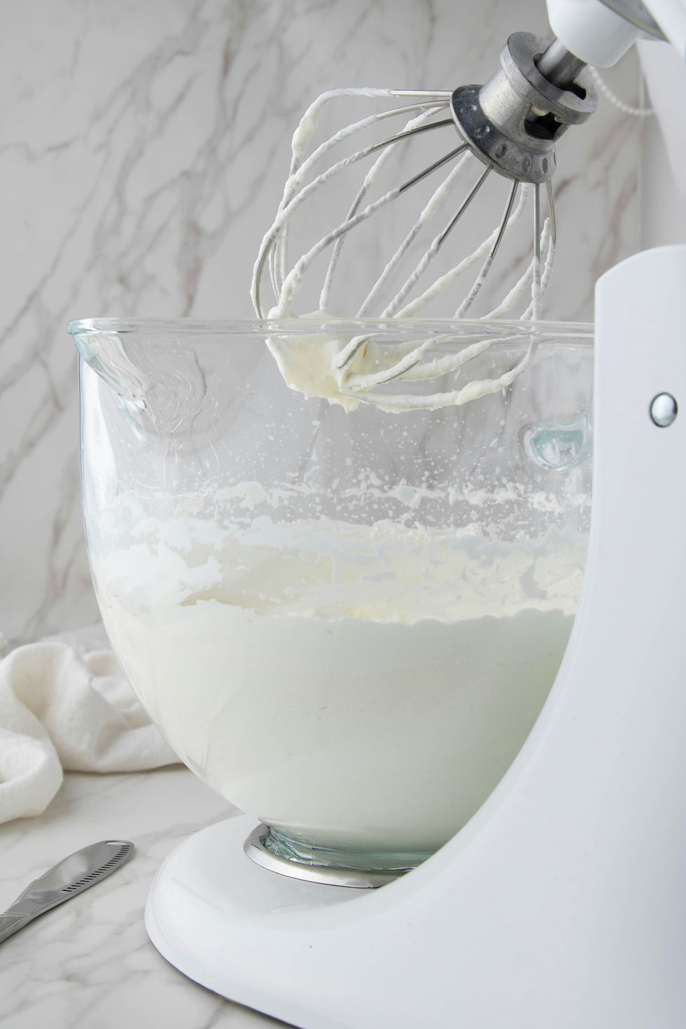 KitchenAid mixer whipping heavy cream as it begins transforming into fresh homemade butter, an essential step in the butter-making process.