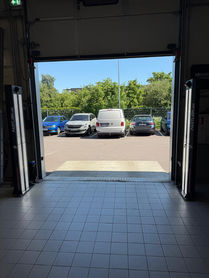 View through open workshop door toward parked vehicles outside