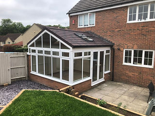 A modern conservatory with large windows and a brown tiled roof