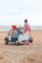 Dominique wandelt op het strand met een lichtblauwe handgemaakte Côté Zoute strandstoel richting haar wagen