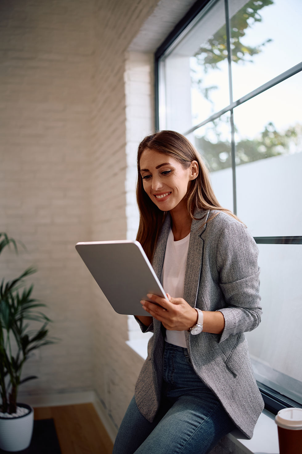 Happy female employee smiles as she looks at a tablet.