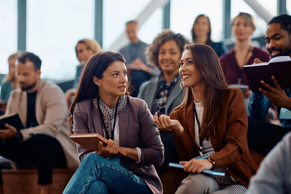 Two happy coworkers smile and chat as they attend a workplace performance workshop with Interplay Advisory