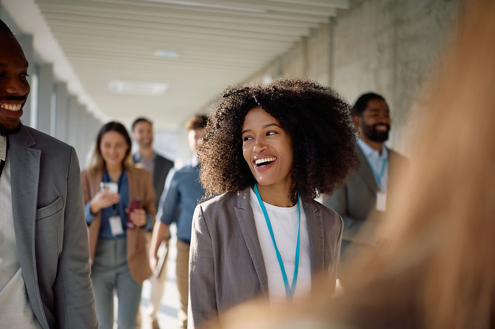 Woman smiles as she walks down the hallway. Her coworkers are blurred in behind her.
