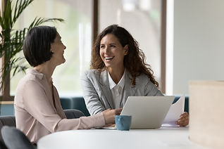 Two happy businesswomen, office employees work in office, laughing, joking during workflow