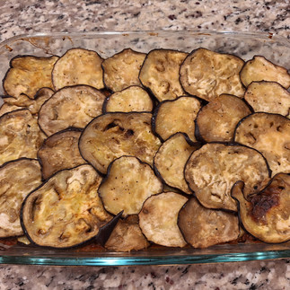 In a large baking dish, layer half of the roasted potatoes on the bottom. - Add a layer of half the roasted eggplant slices. - Spread half of the meat sauce over the eggplant layer. - Repeat the layers with the remaining potatoes, eggplant, and meat sauce. - Pour the creamy topping evenly over the top, spreading it with a spatula to cover the entire surface.