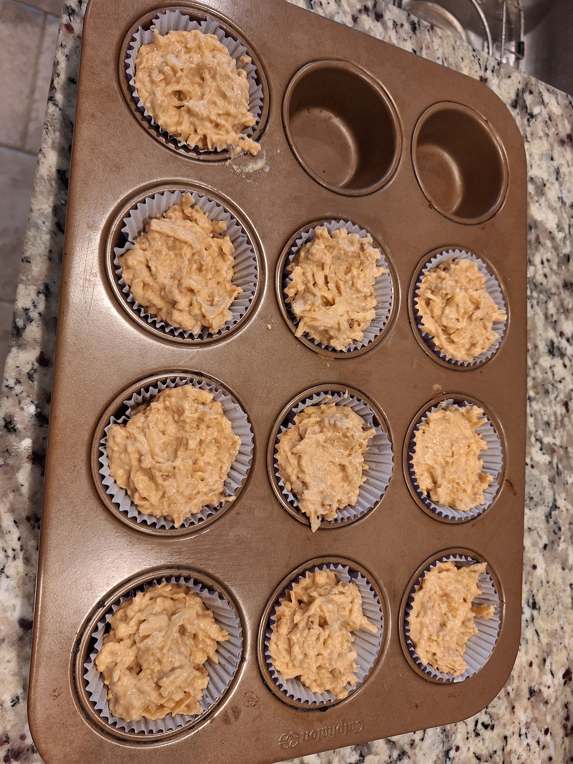 mango puree, milk, egg and vanilla extract with apple and flour mixed in cupcake papers in a cupcake pan