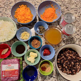 2 lb ground beef 2 tbsp butter 1 large onion, finely diced 1 bell pepper, diced 4 cloves garlic, minced 1 carrot, finely grated 2 tbsp tomato paste 1 can (28 oz) crushed tomatoes 2 cups beef broth 2 tbsp Worcestershire sauce 2 tbsp capers, chopped 2 tsp smoked paprika 2 tsp ground cumin 1 tsp ground coriander 1 tsp dried oregano 1/2 tsp cinnamon 1 bay leaf 2-3 tsp cocoa powder (or a small piece of dark chocolate) 1 tbsp apple cider vinegar Salt and black pepper, to taste 4 cups cooked black and pinto beans