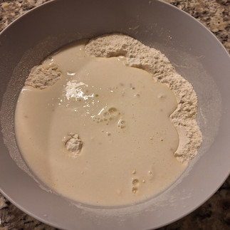 In a large bowl, whisk together all-purpose flour, bread flour, and salt. In a separate bowl or measuring cup, whisk together the warm milk, sourdough starter, and sugar or honey (and yeast, if using). Pour wet into dry, add softened butter, and stir until a shaggy, sticky dough forms. No kneading needed.