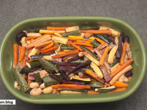 Colorful roasted vegetables in a green dish on a gray surface. Text "aikitchen.blog" appears on a white label in the corner.