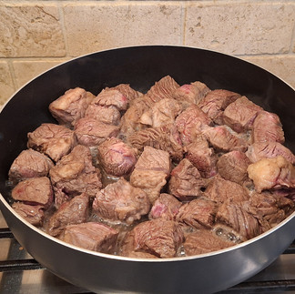 In a heavy skillet or Dutch oven, heat oil over medium-high. Brown beef cubes and short ribs on all sides; set aside. In the same pan, sauté onions until golden (10–15 min). Add garlic for the last minute. Stir in tomato paste and cook until slightly darkened. Add paprika, cumin, salt, and pepper; stir to coat.