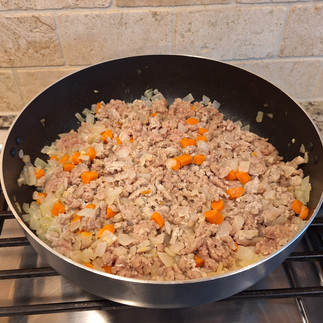 onion on pan with carrots mixed with ginger and garlic with turkey being mixed