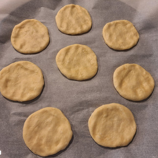 Divide dough into 8 equal pieces. Flatten each into a 3–4 inch circle, keeping the center thinner and edges slightly thicker. Place your chocolate filling (or praline) in the center. Gather the edges and pinch tightly to seal like a dumpling. Roll seam-side down into a smooth ball.