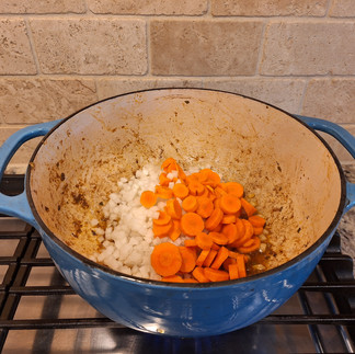 In the same Dutch oven, add the diced onion and sliced carrots. Sauté for about 5 minutes until softened.