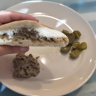 hand holding pita bread stuffed with spread