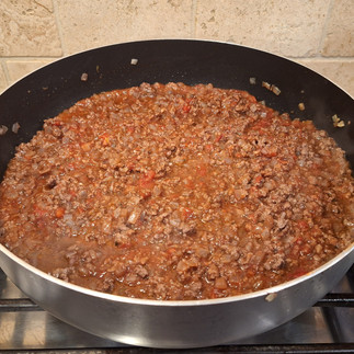 Stir in the crushed tomatoes, tomato paste, red wine (if using), sugar, ground cinnamon, dried oregano, salt, and pepper.