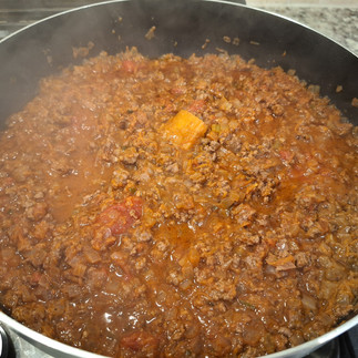 In a large pan, heat butter over medium heat. Add onion, garlic, carrot, and celery. Sauté until softened and lightly golden. Add the ground beef, breaking it apart and browning it evenly. Stir in tomato paste and cook for 1-2 minutes. Add red wine, scraping up any browned bits on the bottom of the pan. Let the wine reduce by half. Pour in the crushed tomatoes, balsamic vinegar, beef broth, and toss in the Parmigiano rind (if using). Simmer over low heat for 45-60 minutes, stirring occasionally. Season with salt and pepper to taste.
