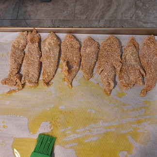 uncooked Oven-Baked Breaded Chicken Tenderloins after baking on a baking sheet still being laid down
