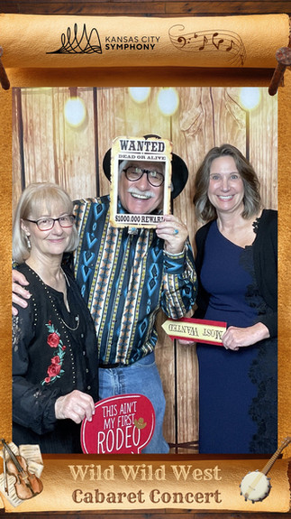 Three people with props pose for the Glam Cam KC photo booth at the KC Symphony event