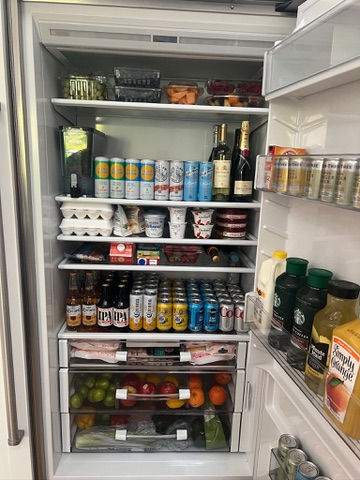 A full fridge with drinks, eggs, fruits, and yogurt. Beverages on the door include juice and bottles. Bright, organized, and well-stocked.