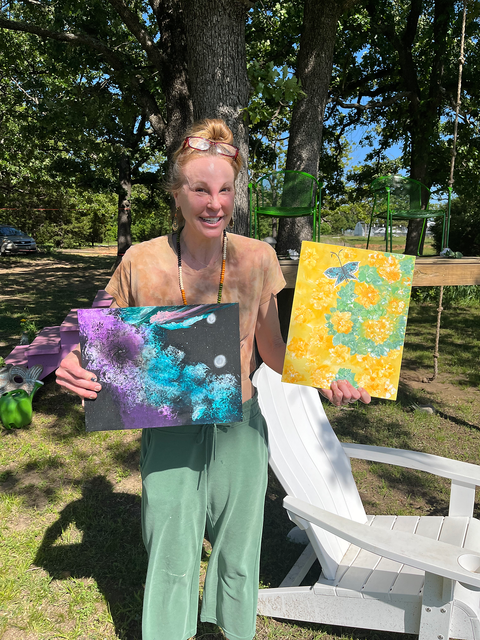 An artist holding two paintings that she finished during a visionary art integration retreat in May 2026.