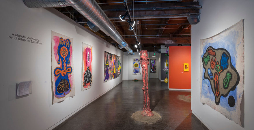 galley with large colorful paintings on walls and red sculptural form in middle of space