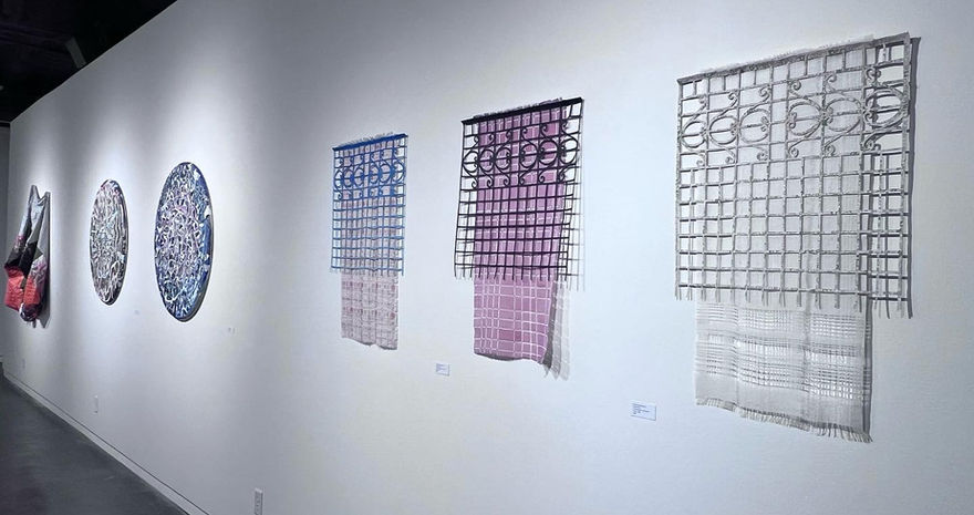 White, red, and blue textile hang from wall. Colorful circle wood collages.