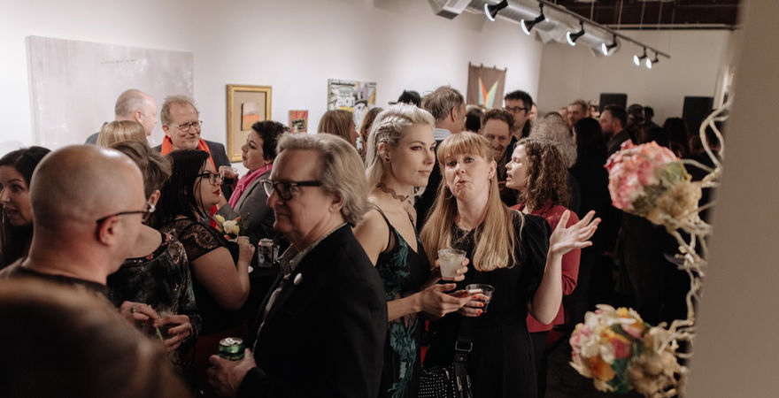 gallery filled with people standing and looking at art