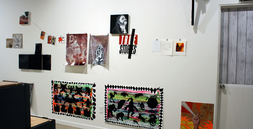 gallery wall with many two dimensional works on paper with paintings and prints 