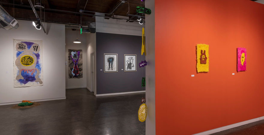 gallery with orange walls and paintings hung on walls 