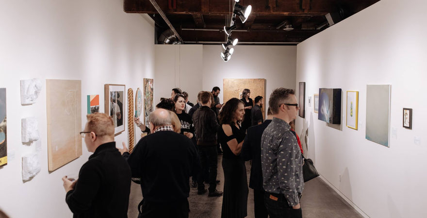gallery filled with people standing and looking at art