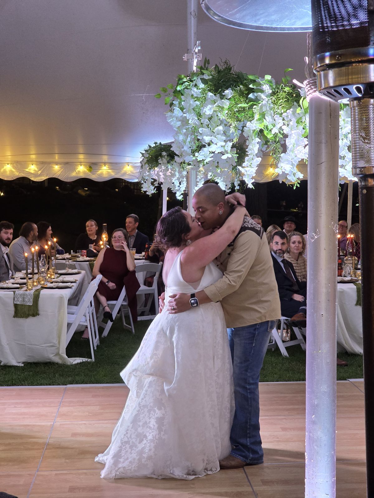A dance beneath the flowers and string lights at the wedding reception.