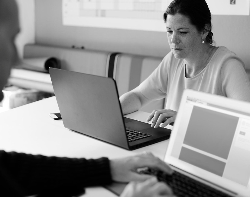 Professional working on a laptop with another person in a collaborative workspace