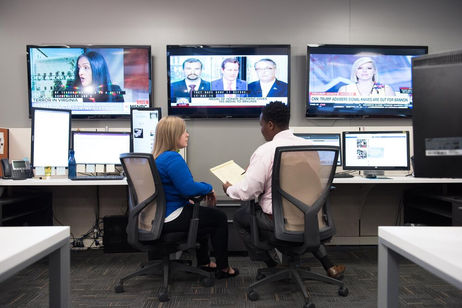 business professionals in office with multiple monitors and tvs
