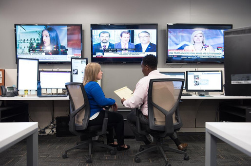 business professionals in office with multiple monitors and tvs