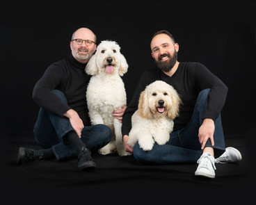 happy gay couple with white poodle chicago studio portrait black background