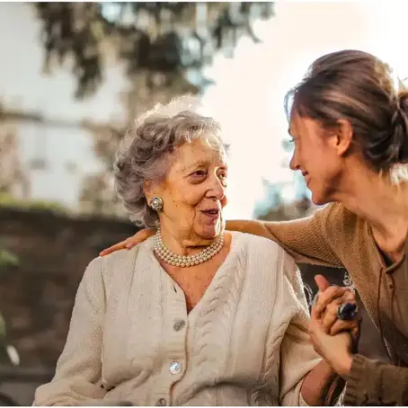 Middle-aged daughter hugging her elderly mother in a peaceful backyard, highlighting the emotional bond and hidden cost of unpaid caregiving.