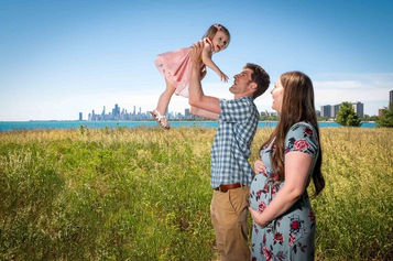Outdoor family portrait holding little girl in air with chicago skyline background