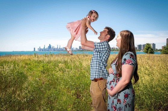 Outdoor family portrait holding little girl in air with chicago skyline background
