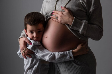 Pregnant mom with son hugging family studio portrait
