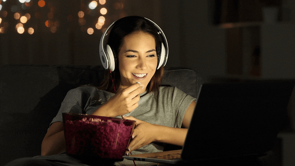A woman wearing headphones eating popcorn and smiling whilst watching her laptop. The words Online Film Festivals are animated on the image.
