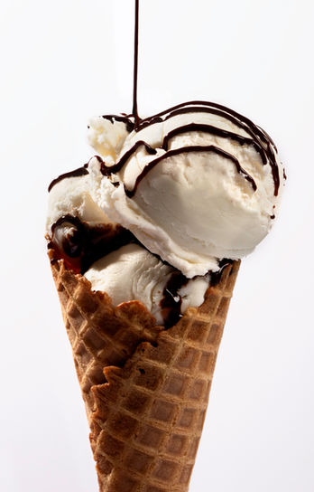 An ice cream cone with vanilla ice cream and chocolate syrup drizzling over top. Taken in the Northern Arizona University photography studio in Flagstaff, Arizona.