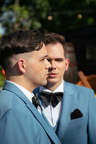 Two men in light blue suits and bow ties at an outdoor event
